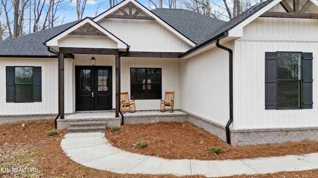 doorway to property featuring covered porch and a shingled roof