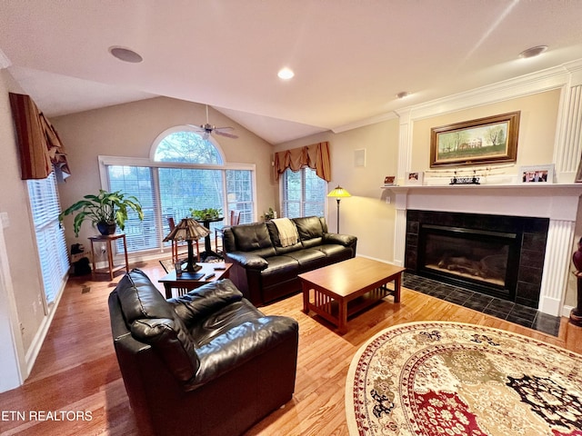 living room with ceiling fan, crown molding, hardwood / wood-style floors, lofted ceiling, and a fireplace