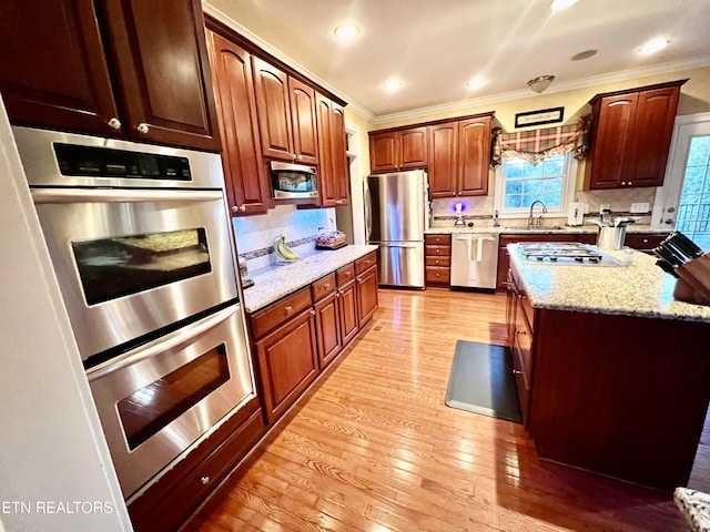 kitchen featuring sink, ornamental molding, light wood-type flooring, tasteful backsplash, and stainless steel appliances