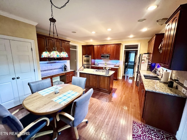 kitchen with appliances with stainless steel finishes, tasteful backsplash, sink, decorative light fixtures, and a center island