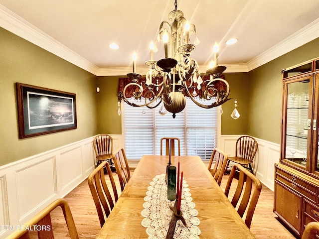 dining area featuring light hardwood / wood-style flooring, ornamental molding, and a notable chandelier