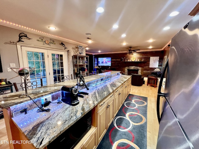 kitchen with stainless steel refrigerator, a large island, light stone counters, and wood walls