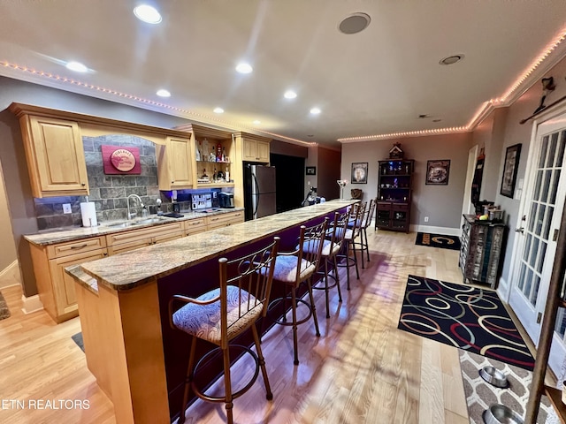 kitchen with a center island, a kitchen breakfast bar, black refrigerator, crown molding, and sink