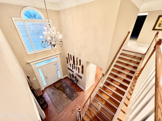 entrance foyer with a chandelier, a high ceiling, hardwood / wood-style flooring, and crown molding