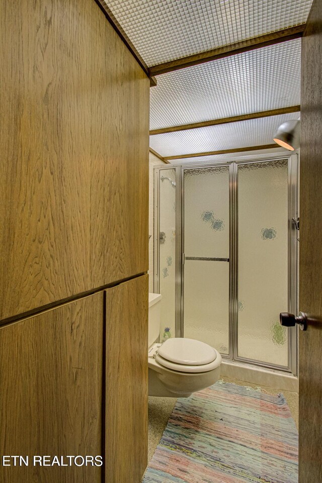 bathroom featuring a shower with door, tile patterned flooring, and toilet