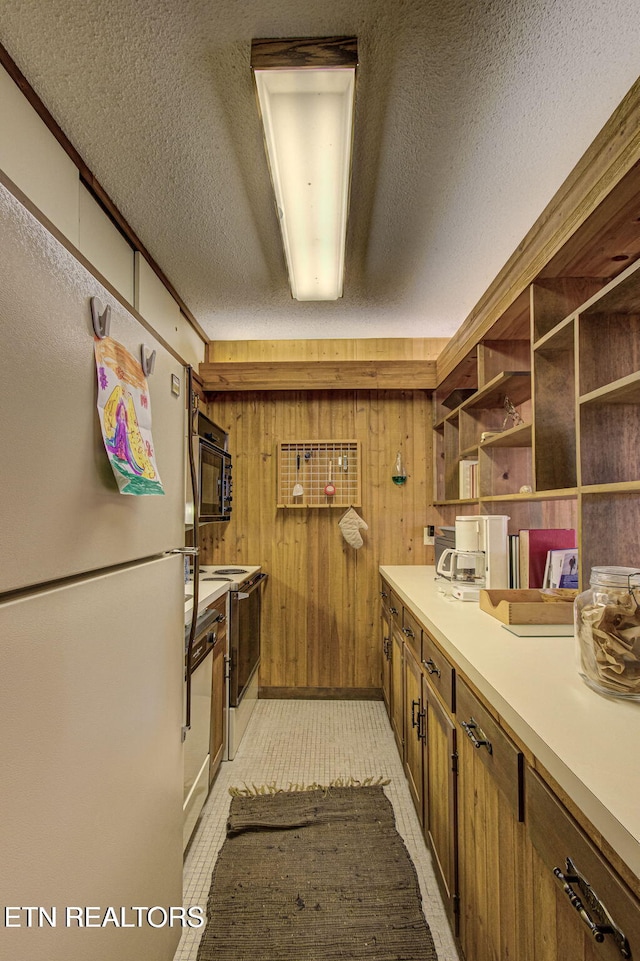 kitchen with electric stove, wood walls, a textured ceiling, and white refrigerator