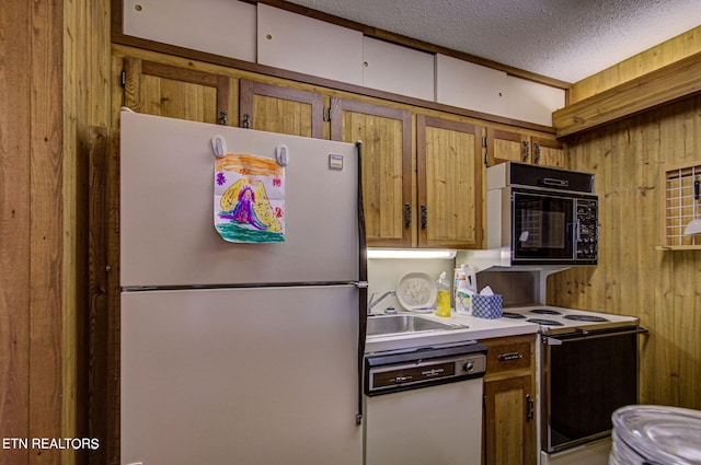 kitchen featuring a textured ceiling, wooden walls, sink, and white appliances