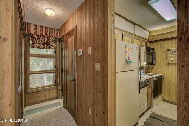 kitchen featuring a textured ceiling, white appliances, and wooden walls