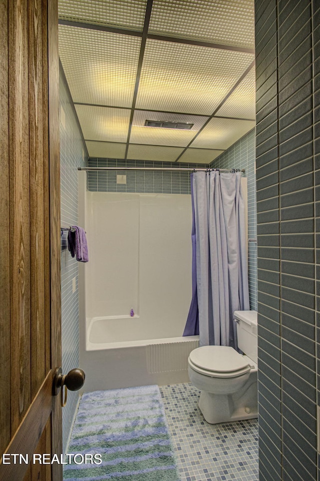 bathroom featuring tile patterned flooring, shower / bath combination with curtain, and toilet