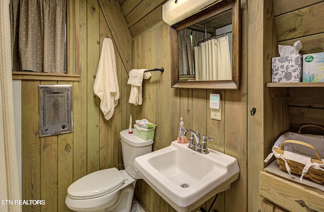 bathroom with wooden walls, sink, and toilet