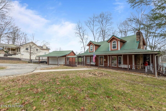 view of front of property with covered porch, a garage, a front lawn, and an outdoor structure