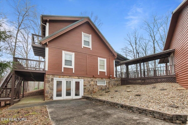 rear view of property featuring french doors, a patio, and a wooden deck