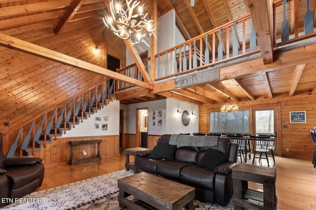 living room with wooden walls, light wood-type flooring, a notable chandelier, beam ceiling, and wood ceiling