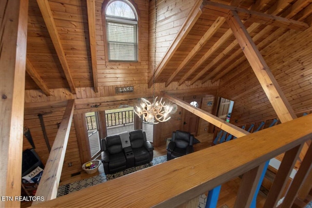 interior space featuring lofted ceiling with beams, an inviting chandelier, wooden walls, and wood ceiling