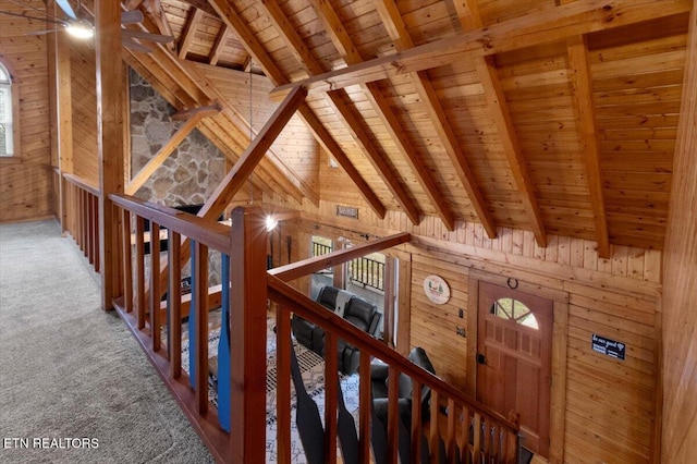 hallway with wooden walls, beam ceiling, high vaulted ceiling, wooden ceiling, and carpet floors