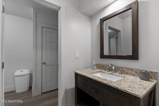 bathroom featuring toilet, vanity, and hardwood / wood-style flooring