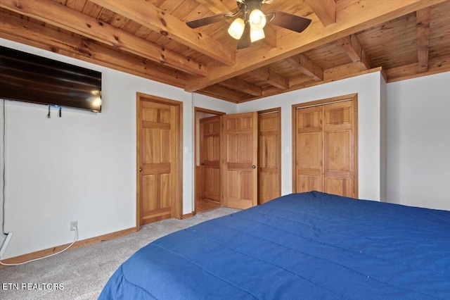 carpeted bedroom with beamed ceiling, ceiling fan, wooden ceiling, and multiple closets