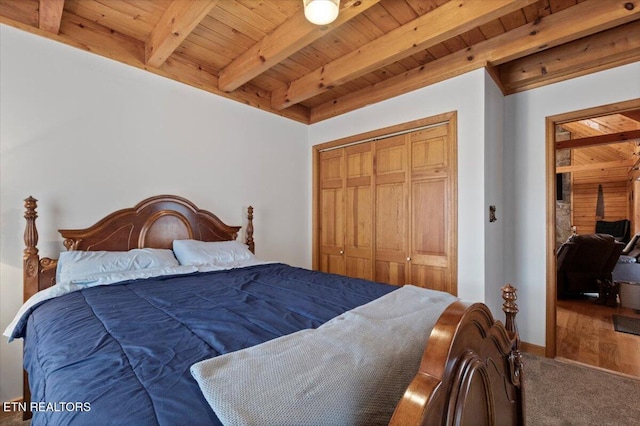 bedroom featuring carpet, beam ceiling, wood ceiling, and a closet