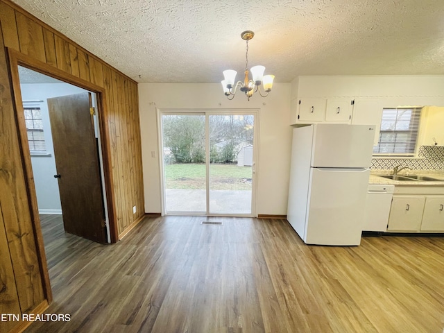 kitchen featuring sink, a chandelier, decorative light fixtures, white appliances, and white cabinets