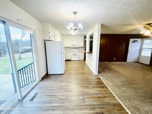 kitchen featuring white appliances, white cabinets, hanging light fixtures, light hardwood / wood-style flooring, and decorative backsplash