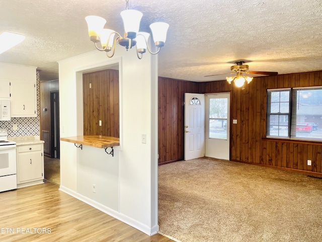 kitchen with white appliances, backsplash, white cabinets, ceiling fan with notable chandelier, and decorative light fixtures