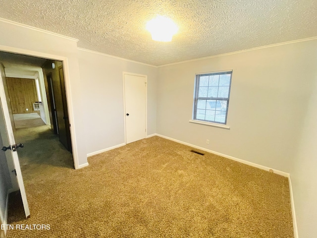 spare room with carpet floors, a textured ceiling, and ornamental molding