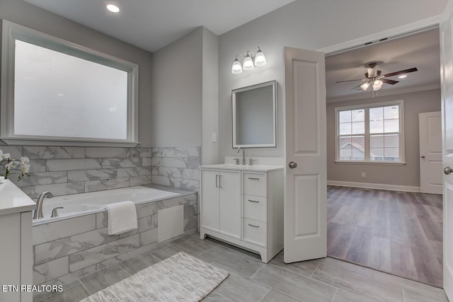 bathroom with tile patterned flooring, vanity, ceiling fan, and tiled tub