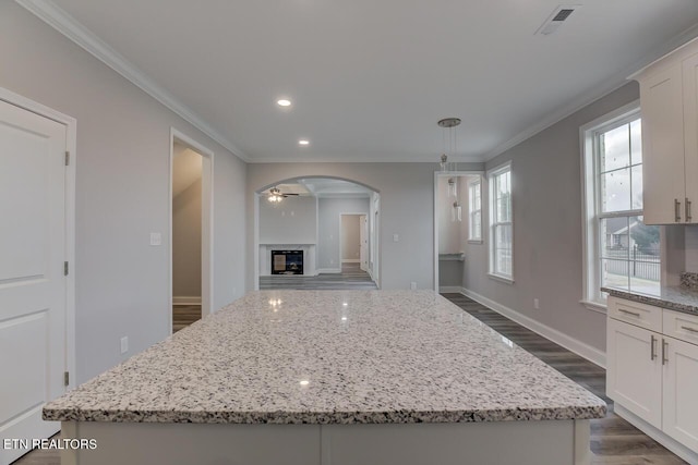 kitchen featuring white cabinets, a center island, and light stone counters