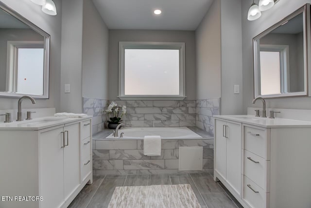 bathroom with tiled tub and vanity