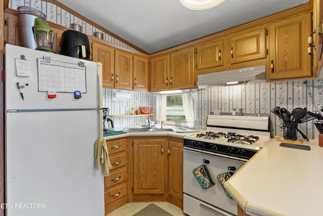 kitchen featuring a textured ceiling, white appliances, sink, and vaulted ceiling