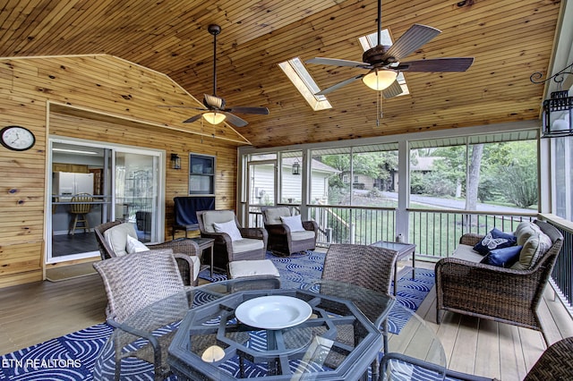 sunroom / solarium featuring a healthy amount of sunlight, vaulted ceiling with skylight, ceiling fan, and wooden ceiling