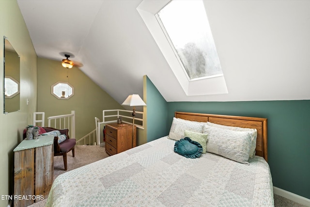 carpeted bedroom with vaulted ceiling with skylight and ceiling fan