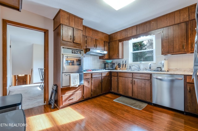 kitchen with tasteful backsplash, dishwasher, light hardwood / wood-style floors, and sink