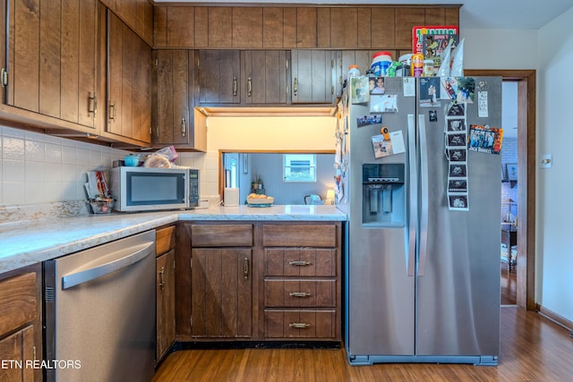 kitchen with decorative backsplash, light wood-type flooring, and stainless steel appliances