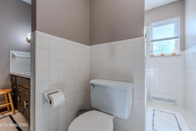 bathroom featuring vanity, toilet, and tile walls