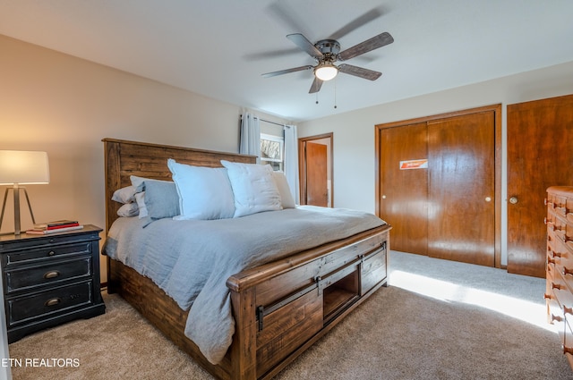 bedroom with ceiling fan, light carpet, and two closets