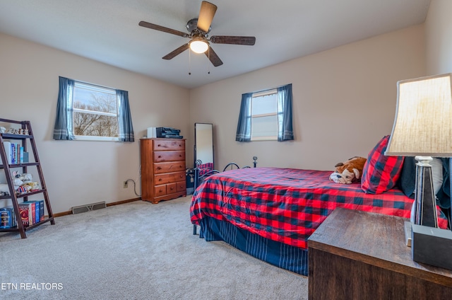 bedroom featuring ceiling fan, light colored carpet, and multiple windows