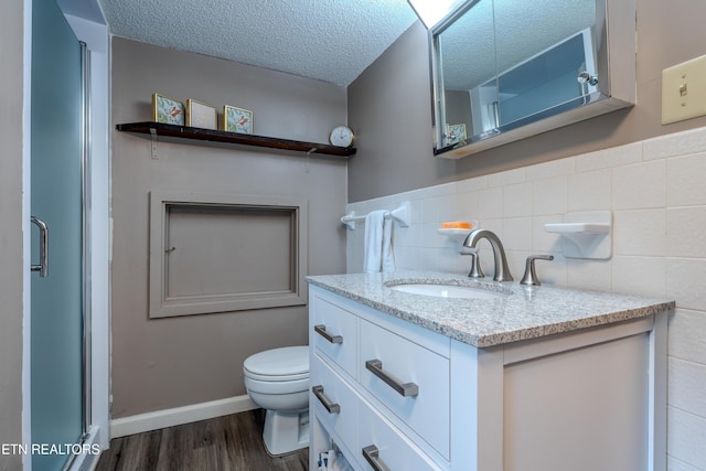 bathroom with hardwood / wood-style floors, vanity, toilet, and a textured ceiling