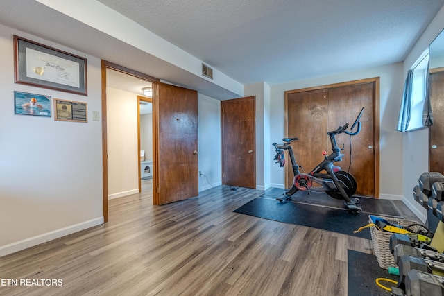 workout room with wood-type flooring and a textured ceiling