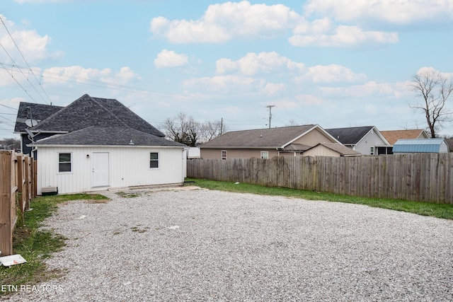 rear view of house with a shingled roof and a fenced backyard