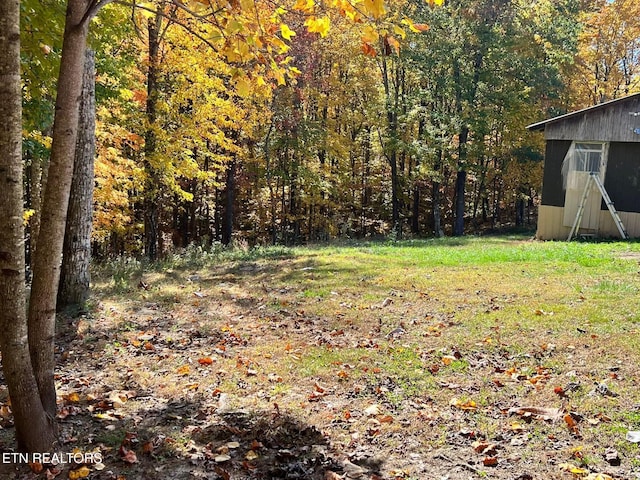 view of yard featuring an outbuilding, a storage shed, and a wooded view