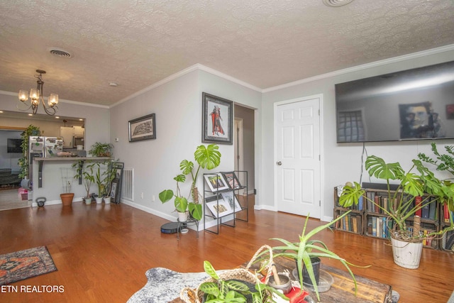 dining room with hardwood / wood-style flooring, a notable chandelier, ornamental molding, and a textured ceiling