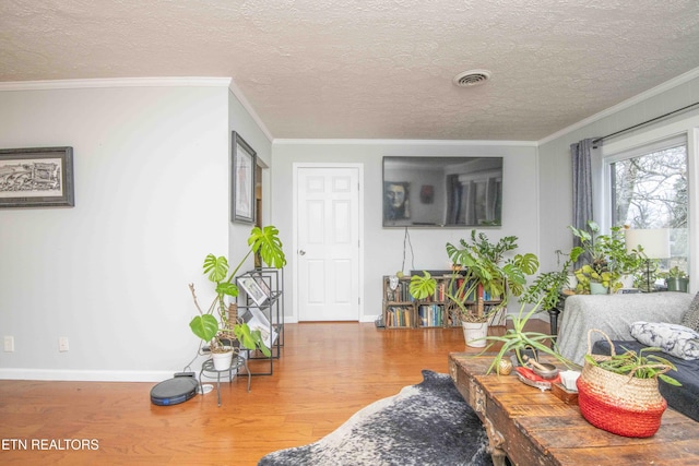 living room with a textured ceiling, wood-type flooring, and crown molding