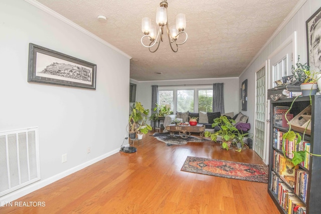 interior space with crown molding, a chandelier, a textured ceiling, and wood-type flooring