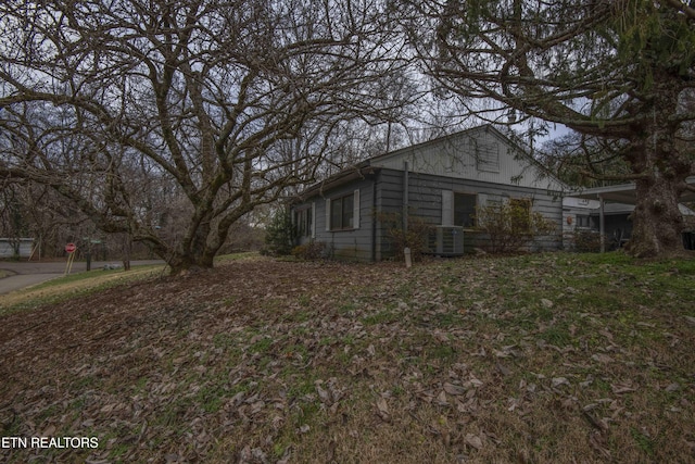 view of side of home featuring central air condition unit and a lawn