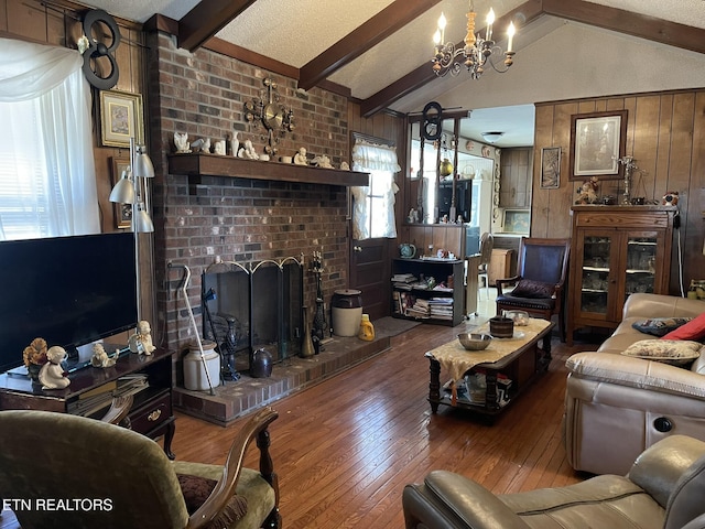 living room with wood walls, wood-type flooring, vaulted ceiling with beams, a chandelier, and a brick fireplace