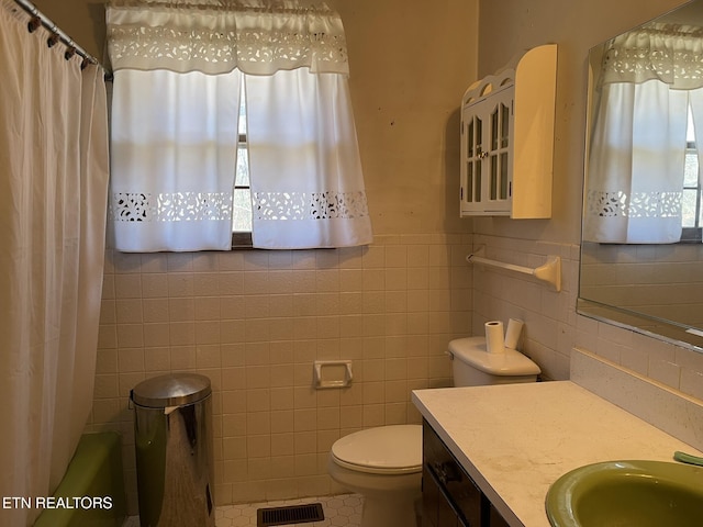 full bathroom with tile walls, shower / bath combination with curtain, tile patterned flooring, vanity, and toilet