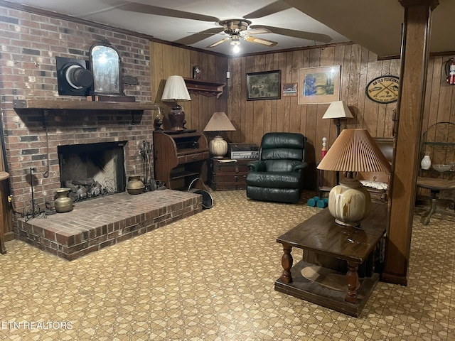 living room with crown molding, ceiling fan, a fireplace, and wood walls