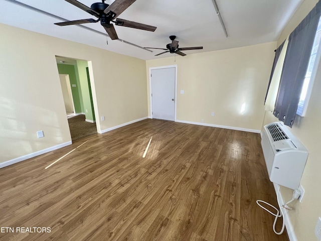 interior space with a wall mounted air conditioner, hardwood / wood-style floors, and ceiling fan