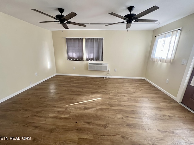 unfurnished room with wood-type flooring, a wall unit AC, and ceiling fan